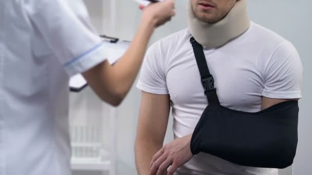 Medico dando conto all'uomo in schiuma collare e braccio fionda, trattamento costoso — Video Stock