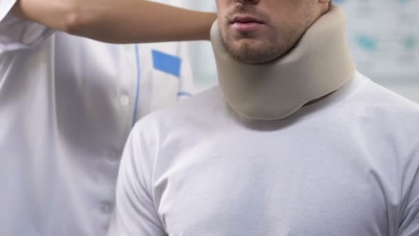 Médico femenino aplicando cuello cervical de espuma de paciente masculino, lesiones en el cuello, tensión — Vídeos de Stock