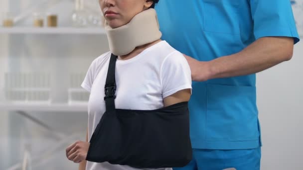 Doctor applying female patient in foam cervical collar arm sling, treatment — Stock Video
