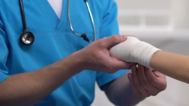 Terapist kadın hastaya bilek elastik şal uygulayarak, spor burkulma sorunu