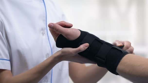 女性治疗师应用泰坦腕支撑男性患者，创伤治疗 — 图库视频影像