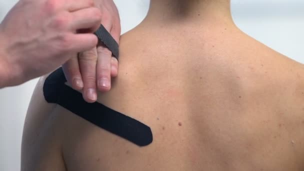 Terapista che applica nastri a forma di Y sulla spalla femminile, traumi sportivi dolore muscolare — Video Stock
