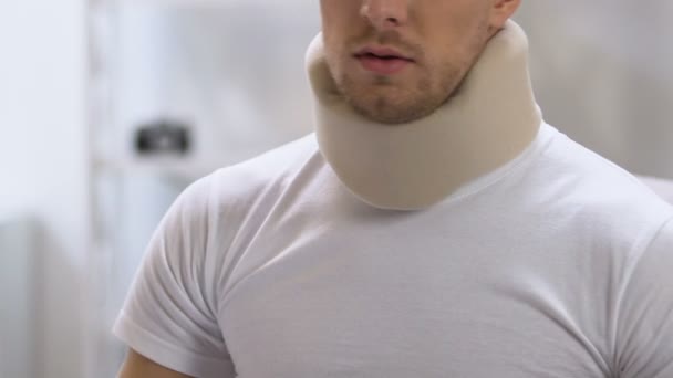 Male in foam cervical collar feeling sharp back pain, problems after trauma — Stock Video