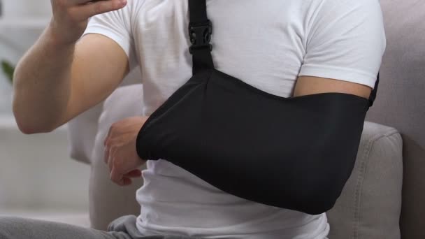 Homem irritado no colo cervical e braço estilingue digitando no telefone, problema de seguro — Vídeo de Stock
