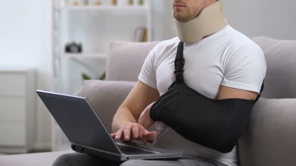 Man with laptop in arm sling and cervical collar feeling pain in neck, trauma — Stock Video