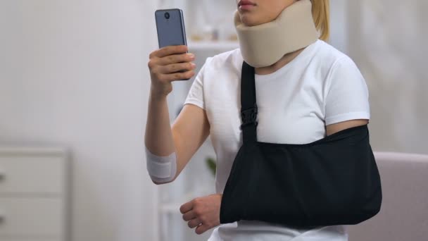 Triste dama en cuello cervical y el cabestrillo del brazo escribiendo en el teléfono inteligente, accidente de coche — Vídeos de Stock