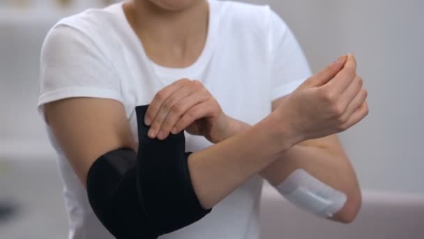 Weibchen trägt Ellenbogen gepolsterte Orthese auf schmerzhaftem Gelenk, orthopädische Unterstützung — Stockvideo