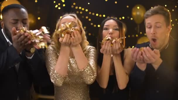 Succesvolle jonge mensen blazen confetti op camera, feestelijke sfeer, plezier — Stockvideo