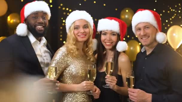Щасливі друзі в капелюхах Санта тости шампанського окуляри камера, Різдвяна вечірка — стокове відео