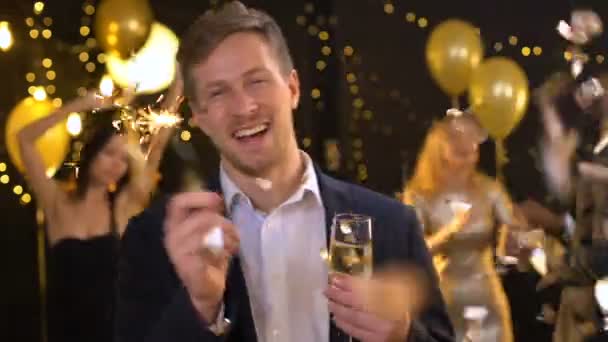 Cheerful drunk man enjoying celebration, holding sparkler and champagne glass — Stock Video