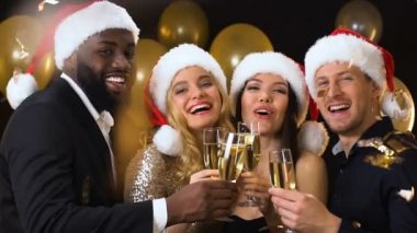 Düşen konfeti altında gözlük clinking Noel Baba şapkalar Multiracial arkadaşlar