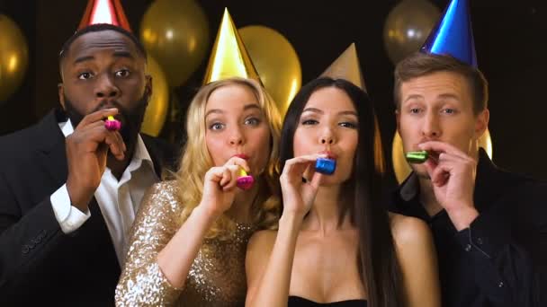 Happy multiracial friends in b-day hats blowing in party ticklers, celebration — Stock Video