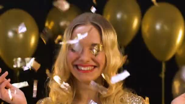 Щаслива блондинка стоїть під падінням конфетті, насолоджуючись вечіркою, святкування — стокове відео