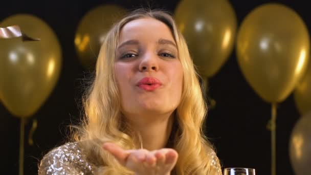 Vrolijke dame met champagne die Air Kiss naar de camera stuurt onder vallende confetti — Stockvideo