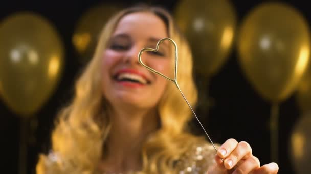 Mooie blonde vrouw houdt hartvormige Bengaalse licht op feest, viering — Stockvideo