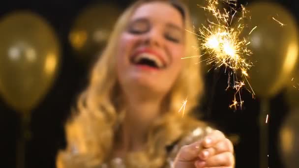 Bastante rubia hembra ondeando bengala luz bajo caída confeti en fiesta, baile de graduación — Vídeos de Stock