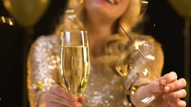 Smiling woman showing glass of champagne and bengal light to camera, party — Stock Video