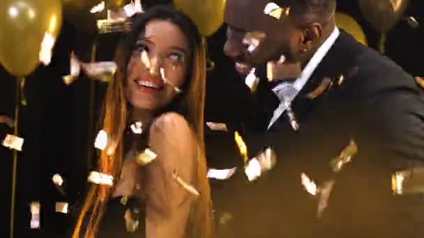 Preto homem dança com ásia mulher no noite clube sob queda confetti Relaxe — Vídeo de Stock
