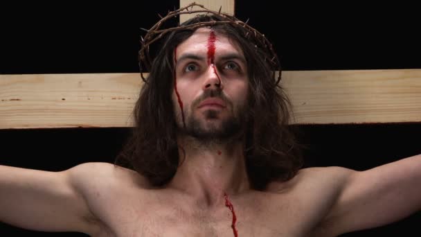Jesus med blödning kropp korsfäste på korset och ser till himlen, närbild — Stockvideo