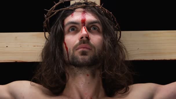 Ісус Христос з кровоточивістю обличчя дивиться на камеру, розп'яття на Хресті, гріхи — стокове відео