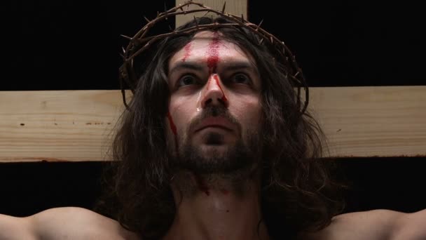 Verängstigter Jesuschrist mit blutendem, am Kreuz gekreuzigten Körper blickt in die Kamera — Stockvideo