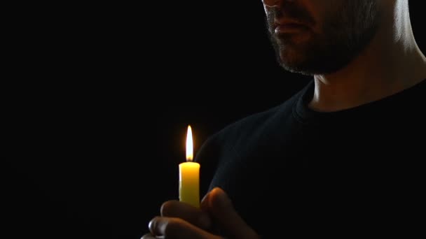 Ember gyertyával keres a mennybe, kérve Istent kegyelemért, imádkozva a templomban — Stock videók