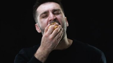 Aç erkek açgözlülükle koyu arka plan, bulimia sorun karşı pasta yeme