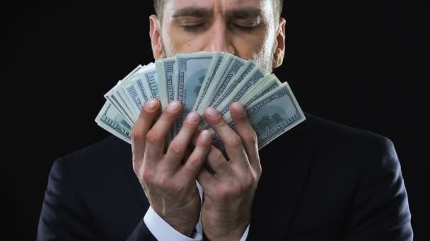 Жадный бизнесмен гладит лицо банкнотами по долларам, наслаждаясь богатством — стоковое видео