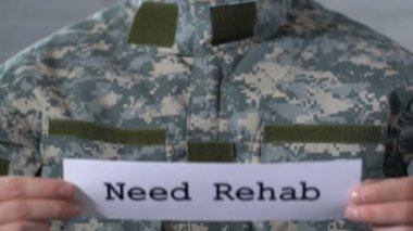 Erkek askerin elinde kağıt üzerinde yazılı rehabilitasyon ihtiyacınız var, savaş gazileri için yardım
