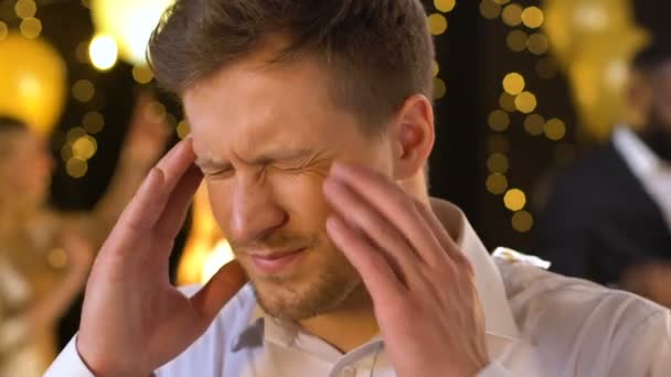 Young male suffering headache at club, massaging temples and looking around — Stock Footage Young male suffering headache at club, massaging temples and looking around Stock Video