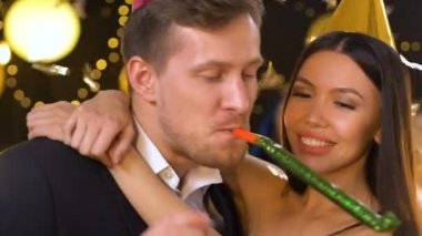 Mutlu çok ırklı çift doğum günü kutluyor, parti üfleyici üfleme ve gülüyor