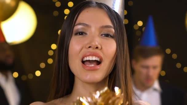 快乐的亚洲女人吹在纸屑上，并在聚会上，庆祝空气吻 — 图库视频影像