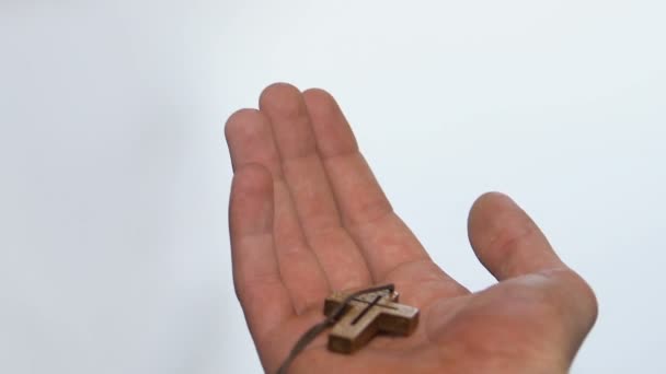 Человек держит деревянный крест в кулаке, принимает и впускает Бога в свою веру в сердце — стоковое видео