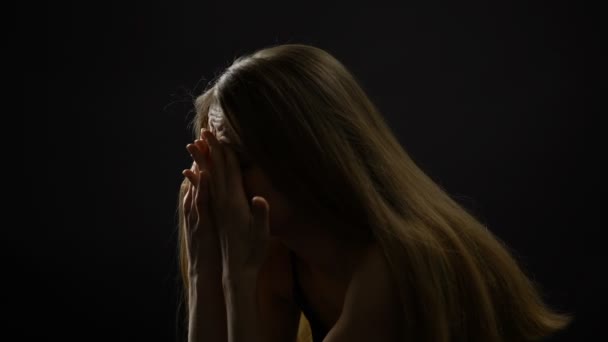 Upset woman sitting alone against dark background, frustration, life problems — Stock Video