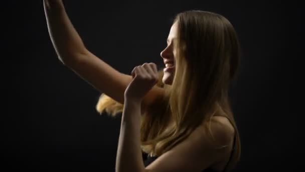 Fröhliche Dame tanzt vor schwarzem Hintergrund, feiert Erfolg, Entspannung — Stockvideo