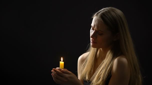 Mujer religiosa apagando la vela después de la oración, fe profunda y arrepentimiento — Vídeos de Stock