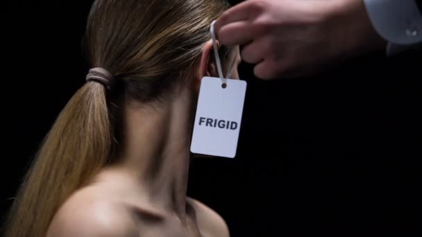 Hombre mano poniendo etiqueta frígida en oreja femenina imponiendo inseguridades sexuales en pareja — Vídeos de Stock