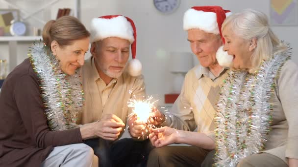 Jubilados emocionados en sombreros de santa iluminación bengala luz, celebración de Año Nuevo — Vídeos de Stock