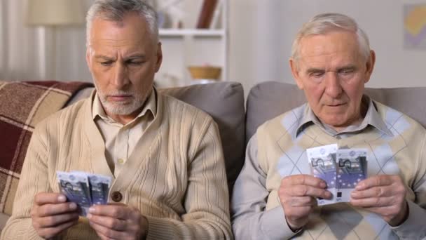 Ledsen åldern män som innehar euro räkningar söker kamera, brist på pengar, sociala problem — Stockvideo