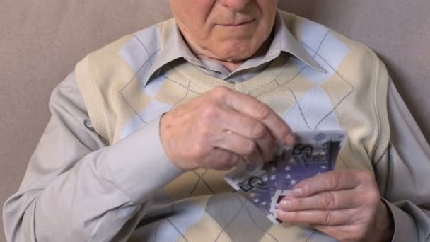 Пожилой человек, который считает счета в евро, смотрит в камеру, банковские инвестиции, пенсионный кредит — стоковое видео