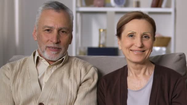 Feliz aposentado casal olhando câmera sentado sofá, velhice vitalidade, saúde — Vídeo de Stock