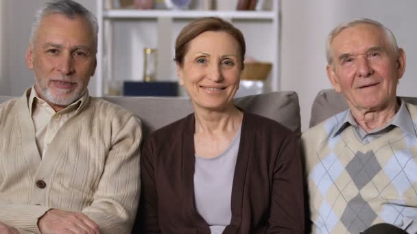 Здорові літні люди посміхаються на камеру сидячи диван, будинок престарілих, гарний настрій — стокове відео