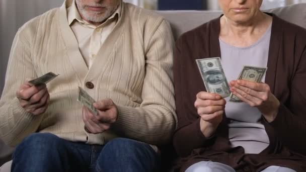 Descontente casal maduro mostrando dólares na câmera, reforma da pensão, baixo orçamento — Vídeo de Stock