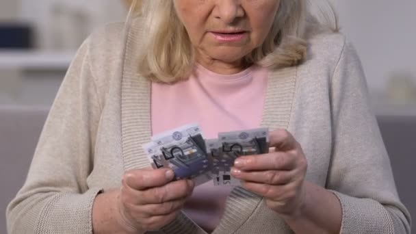 Несчастная старуха считает банкноты евро, небольшую пенсию, нехватку денег, бедность — стоковое видео