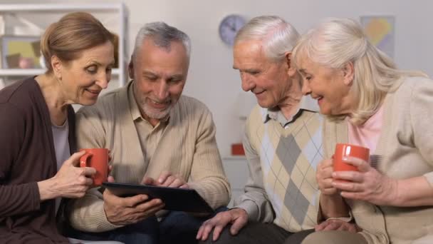 Amigos ancianos modernos utilizando la aplicación bancaria en la tableta, sonriendo a la cámara, dispositivo — Vídeo de stock