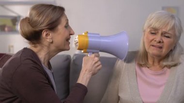 Yaşlı kadın arkadaşına megafonla bağırıyor, işitme kaybı hastalığı, sorun