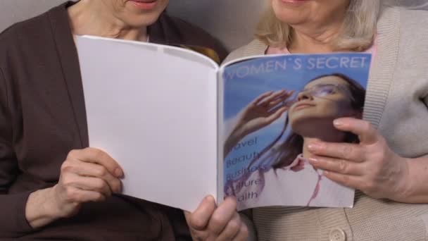 Пожилые современные женщины читают журнал, в поисках рецепта красоты, косметологии — стоковое видео