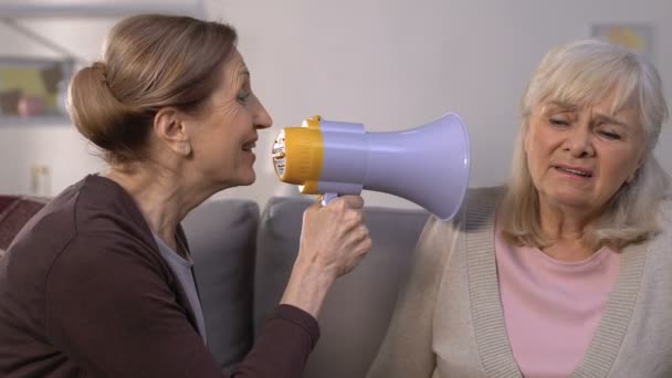 Old woman shouting through megaphone to friend, hearing loss illness, problem — Stock Video