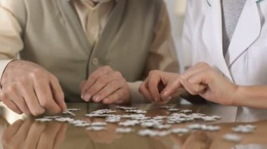 Kadın caregiver yaşlı adam bulmaca masası, zihinsel eğitim, Alzheimer yapıyor yardım