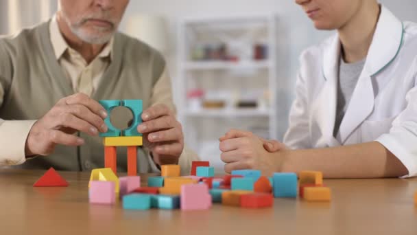 Trabalhador hospitalar ajudando paciente demência combinar blocos de cores, exercício cerebral — Vídeo de Stock